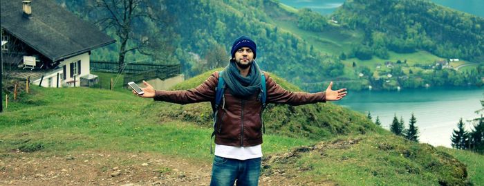 Portrait of young man with arms outstretched standing on mountain