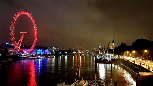 Illuminated ferris wheel in city at night