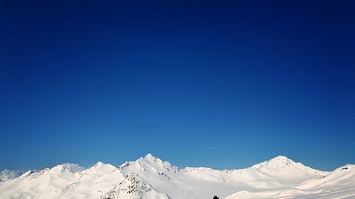 Scenic view of snowcapped mountains against clear blue sky