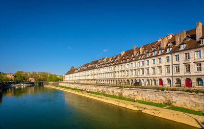 Buildings at waterfront against blue sky