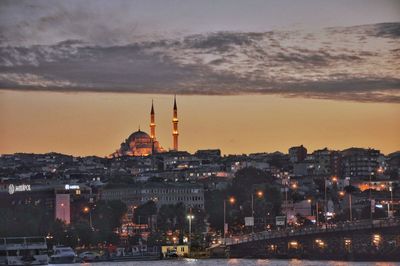 Illuminated buildings against sky during sunset in city