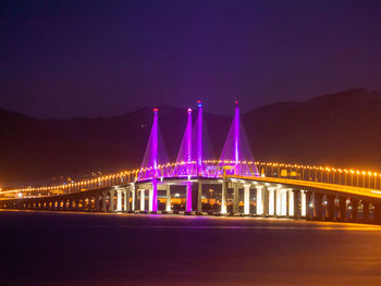 Illuminated bridge over river at night