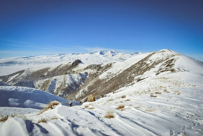 Scenic view of snowcapped mountains against clear blue sky