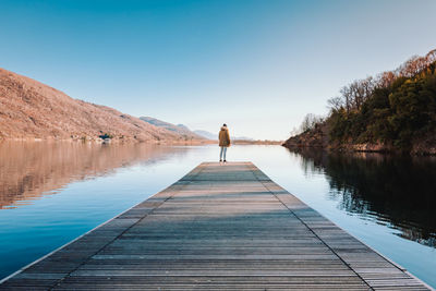 Pier over lake against clear blue sky