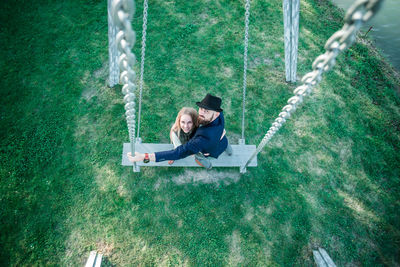 High angle view of couple standing on swing at park