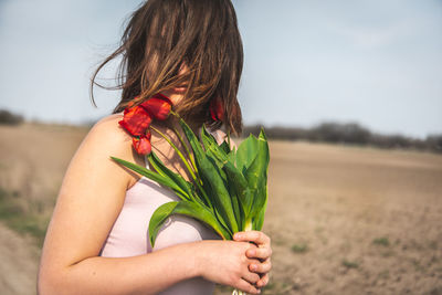 Midsection of woman holding flower against sky