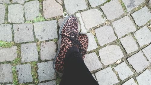 Low section of woman standing on cobblestone