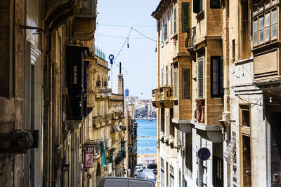 Narrow street amidst buildings against clear sky