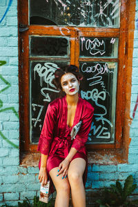 Portrait of young woman against blue door