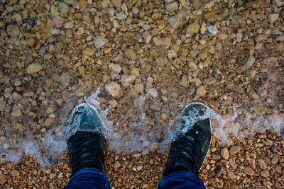 Low section of person standing on pebbles