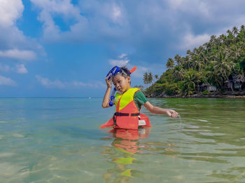 Boy in sea against sky