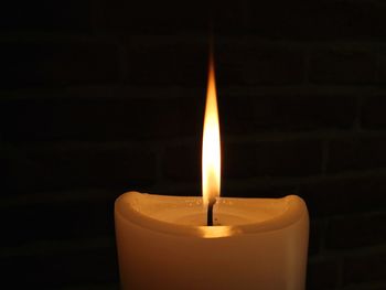 Close-up of lit candle in darkroom