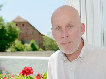 Portrait of man standing against window at home