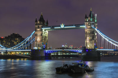 Illuminated tower bridge over thames river against sky at night