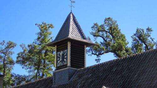 Low angle view of trees and building against sky