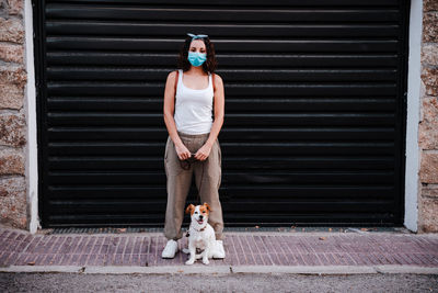 Full length of woman with dog against shutter