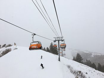 Ski lift over snow covered mountains against sky