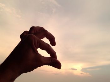 Cropped image of person holding umbrella against cloudy sky