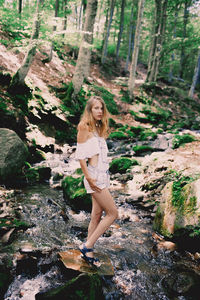 Happy tourist girl teenager in forest near to the cold fresh stream river at the waterfall shypit, cascade in pylypets in the forest. carpathian mountains