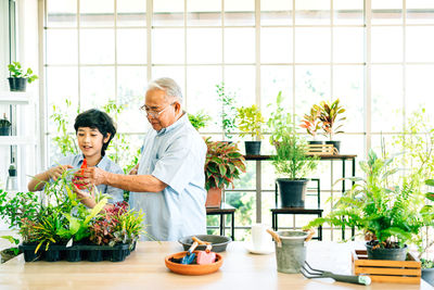 Senior man assisting grandson in greenhouse