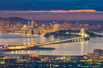 Illuminated bridge over river at night