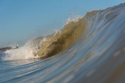 Waves splashing on shore against clear sky