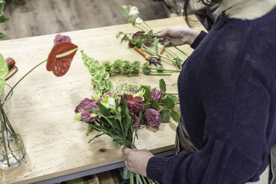 Midsection of florist holding flower at shop