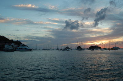 Sailboats in sea against sky at sunset