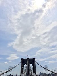 Low angle view of suspension bridge against cloudy sky