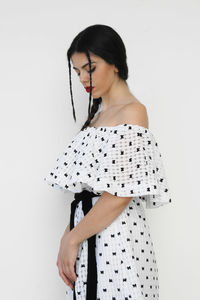 Side view of young woman wearing dress against white background