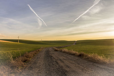 Road amidst field against sky