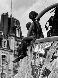 Low angle view of statue by building against sky