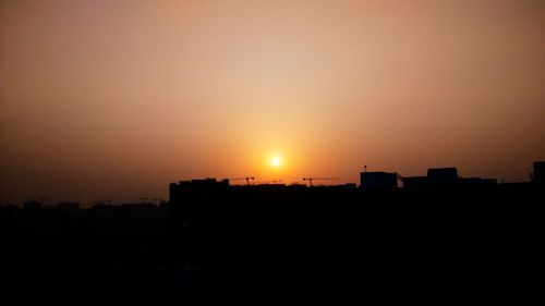 Silhouette cityscape against sky during sunset