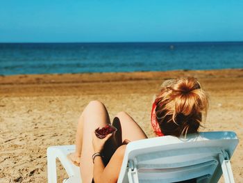 Rear view of woman sitting on beach