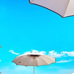 Low angle view of parasol against blue sky