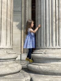 Side view of girl standing on column