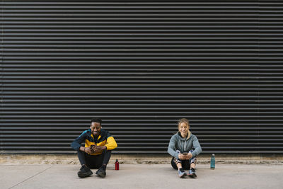 Portrait of friends sitting on road in city