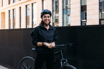 Portrait of smiling woman with bicycle standing outdoors