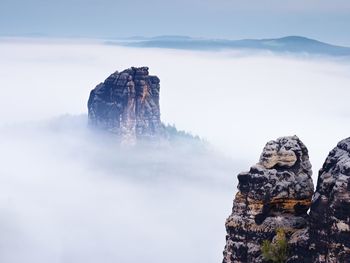 Sharp sandstone rock empire sticking out from heavy fog. deep misty valley full of creamy mist. 