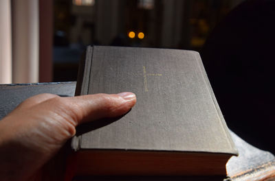 Cropped hand holding bible at pew in church