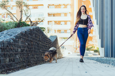 Woman walking with dog on footpath