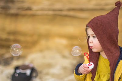 Close-up of girl blowing bubbles outdoors