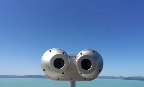 Close-up of coin-operated binoculars against sea