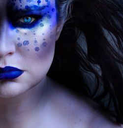 Cropped portrait of shirtless woman with blue make-up