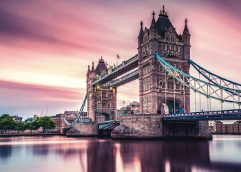 Tower bridge over river against cloudy sky