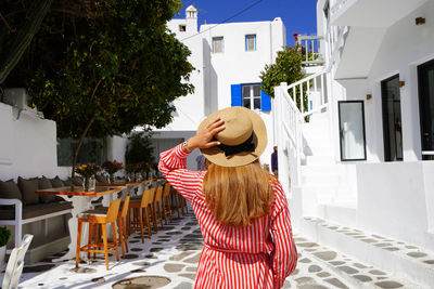 Beautiful fashion girl visiting mykonos island with whitewashed houses. summer vacation in europe.