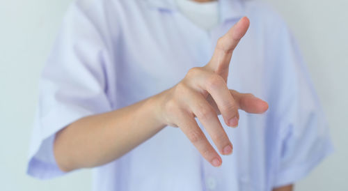 Midsection of female doctor gesturing against wall
