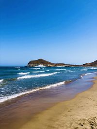 Scenic view of beach against clear blue sky