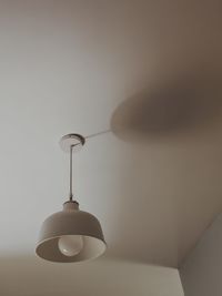 Close-up of light bulb hanging against wall at home