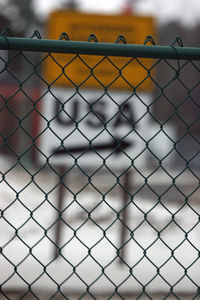Close-up of chainlink fence against sign board